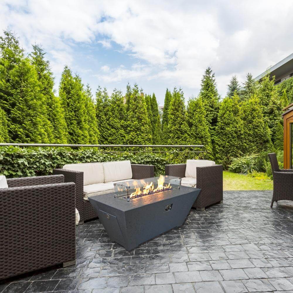 Athena Olympus rectangular concrete fire pit table in a cozy outdoor patio setting with seating.