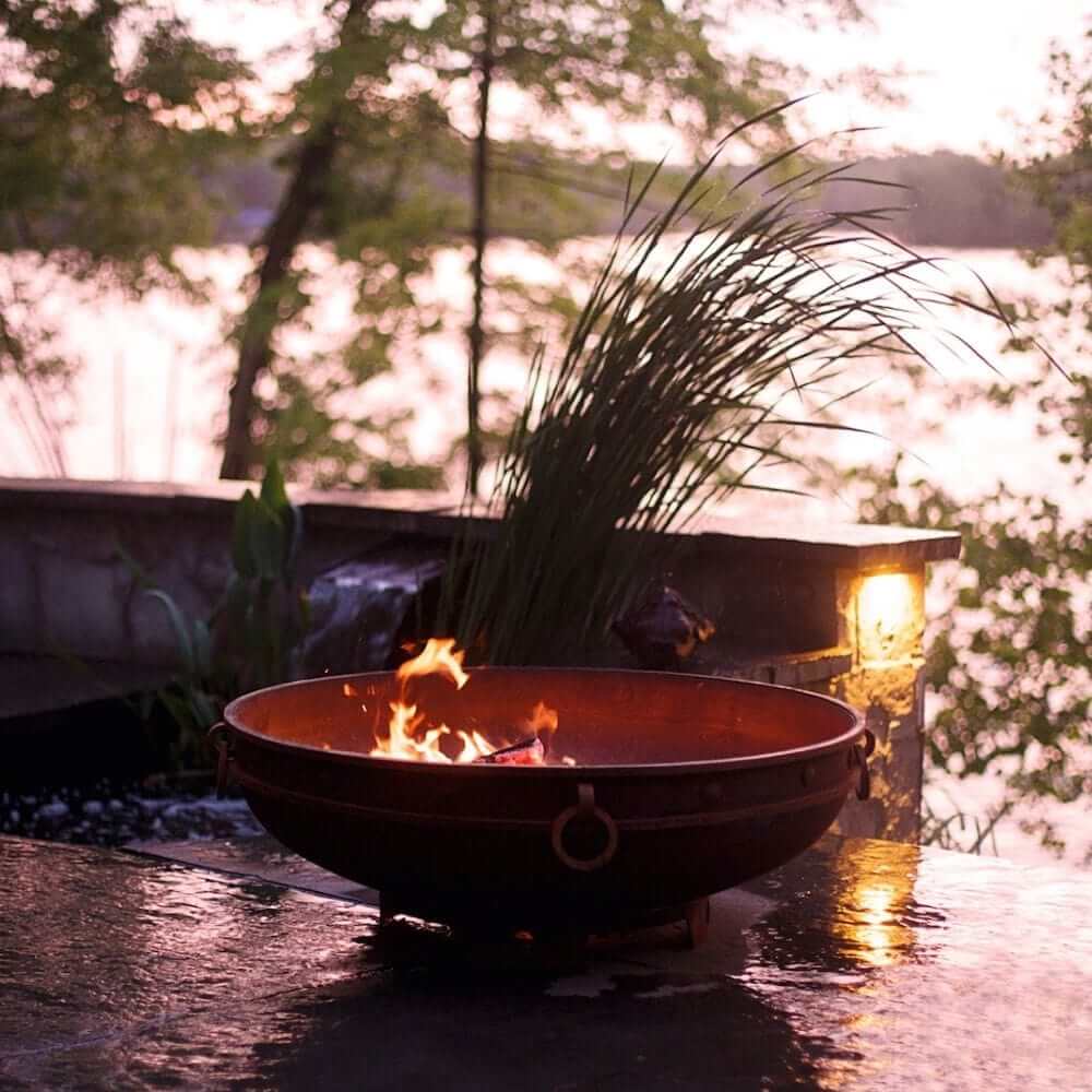 Fire Pit Art Emperor 37-Inch Handcrafted Carbon Steel Gas Fire Pit - next to some plants