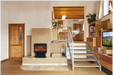 Amantii FS-26-922-LUMINA Freestanding Electric Fireplace - Modern living room with a fireplace, staircase, and kitchen in the background.