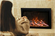 Amantii TRD-30-BESPOKE Electric Fireplace - Person wearing a sweater sitting in front of a fireplace with flames.