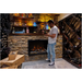 Amantii TRD Lumina Electric Fireplace - Man standing in a wine cellar with a lit fireplace and shelves filled with bottles.