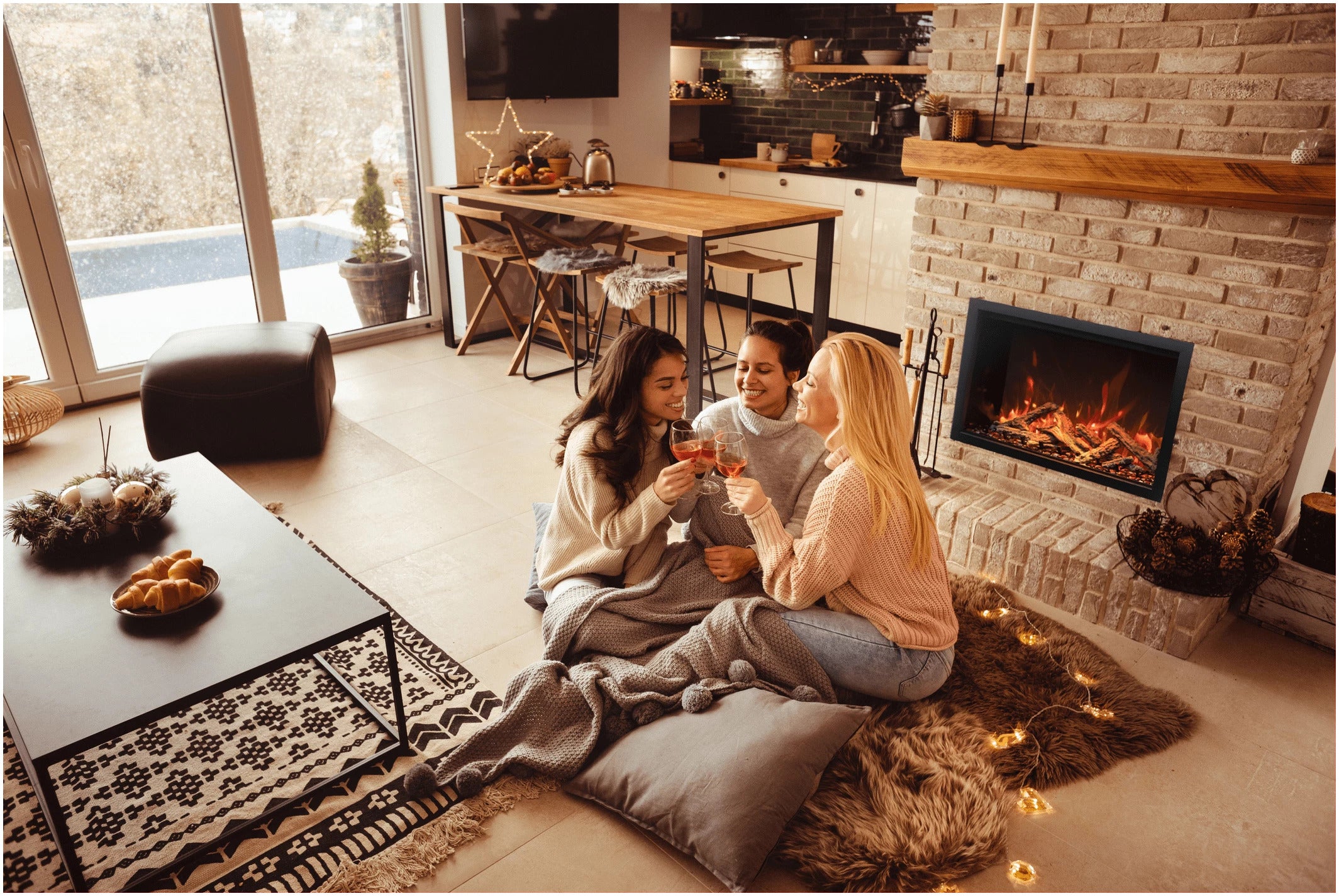 Amantii TRD-30-BESPOKE Electric Fireplace - Three women sitting on a rug in front of a fireplace in a cozy living room.