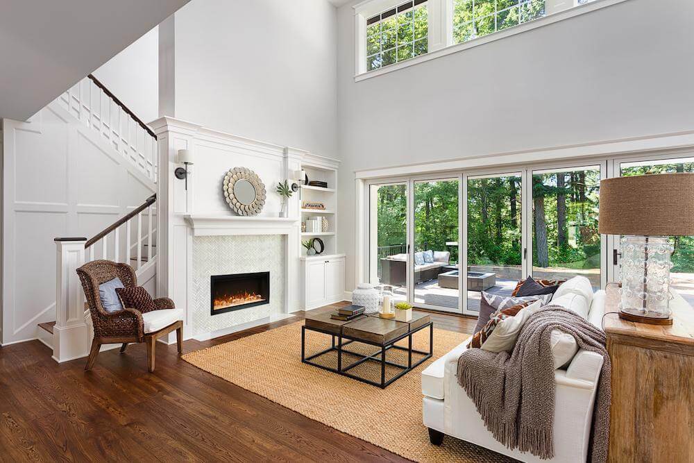 Amantii Symmetry XT Premium Electric Fireplace with Smart Control - A cozy living room featuring a warm fireplace and an elegant staircase