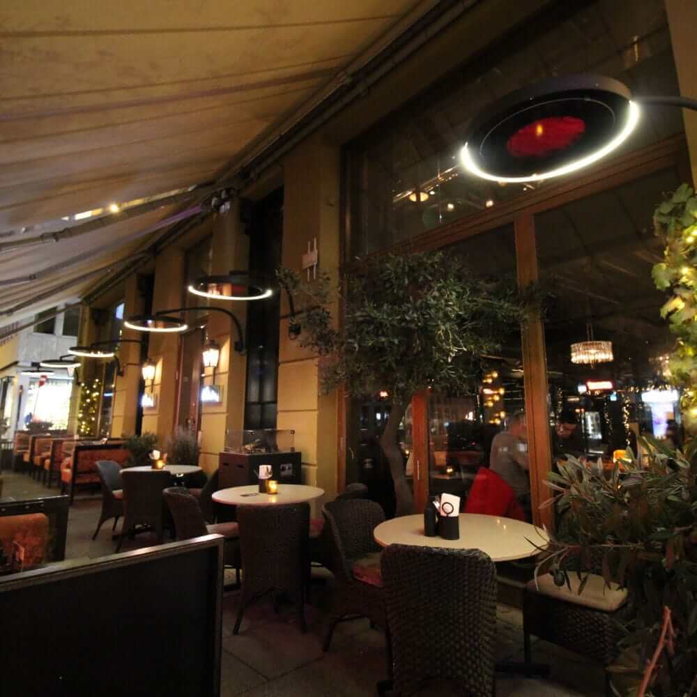 Elegant outdoor dining area featuring Bromic Eclipse Smart-Heat ceiling-mounted electric heaters for warmth and style.