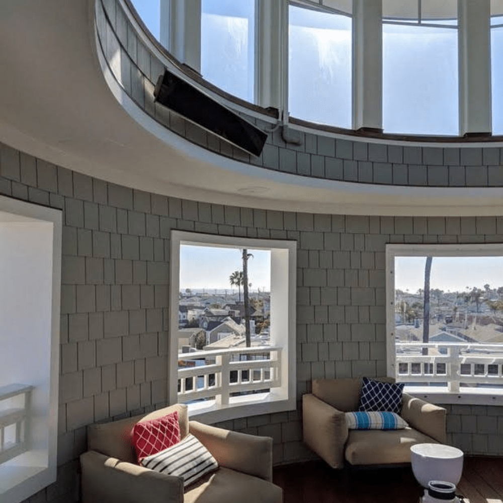 Bromic Platinum 208V electric heater mounted in modern round room with large windows and cozy seating.