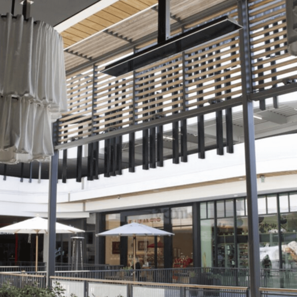 Interior view of a modern shopping center featuring sleek design elements and patio umbrellas.