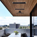Stylish outdoor space featuring Bromic Platinum electric heaters mounted on a wooden ceiling with city view.