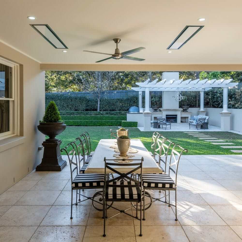 Outdoor dining area with a table and chairs, featuring a stylish patio heater and landscaped garden.