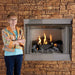 Empire Carol Rose Premium Outdoor Vent Free Gas Fireplace - Woman standing next to a stone fireplace with a lit fire