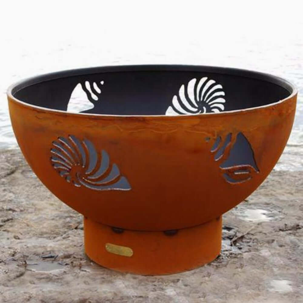 Fire Pit Art Beachcomber 36-Inch Handcrafted Carbon Steel Gas Fire Pit - Decorative fire pit with shell designs on a wooden surface