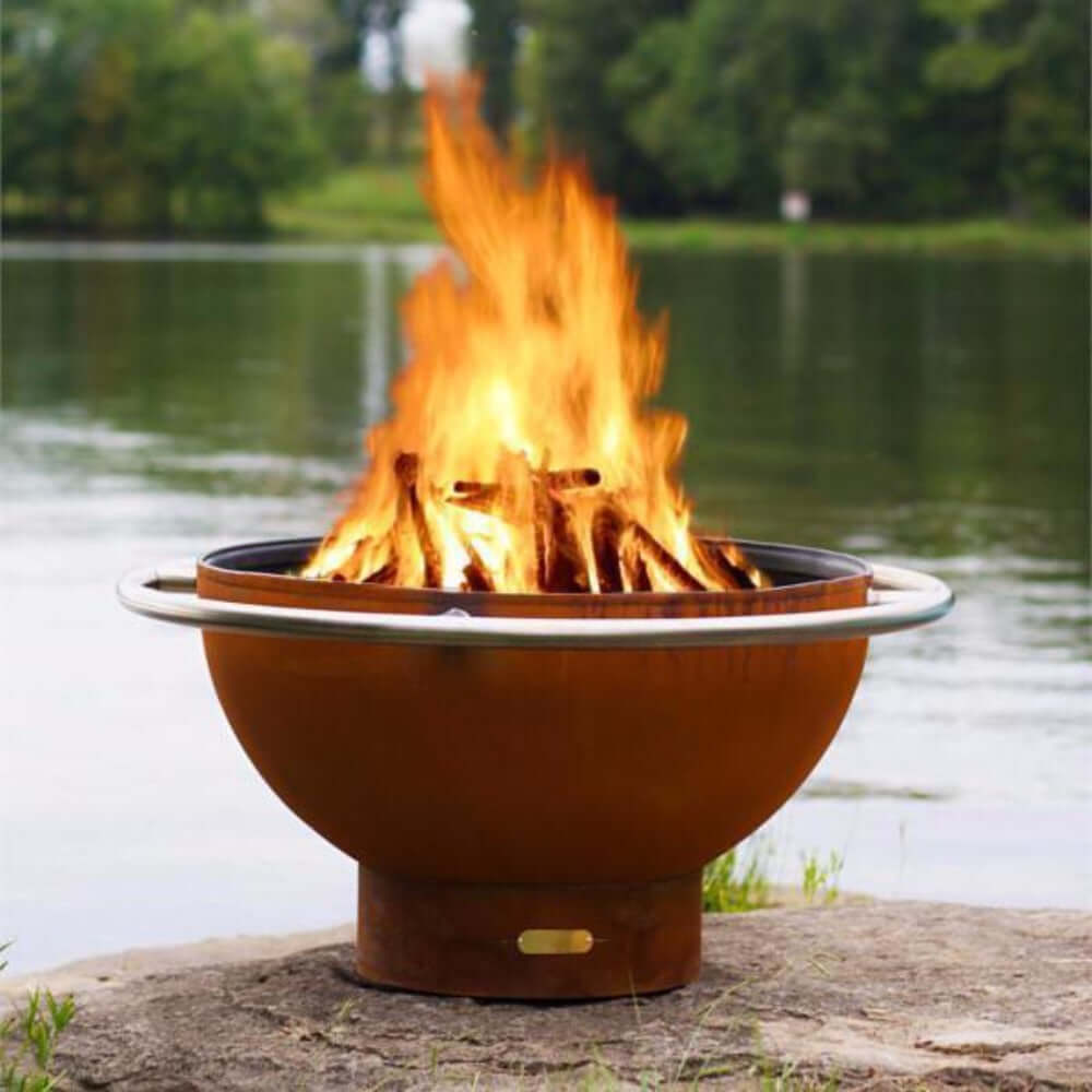 Fire Pit Art Bella Luna 48-Inch Handcrafted Carbon Steel Fire Pit (BL) - Fire pit with flames burning in a natural setting by a body of water.