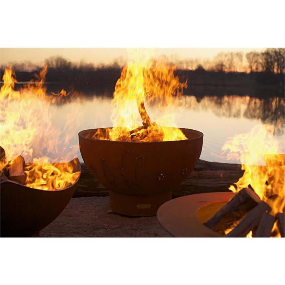 Fire Pit Art Crater 36-Inch Handcrafted Carbon Steel Fire Pit (CTR) - Three fire pits with flames burning near a body of water.