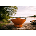 Fire Pit Art Manta Ray 36-Inch Handcrafted Carbon Steel Gas Fire Pit - Orange fire pit on a rock by a lake with trees in the background