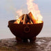 Fire Pit Art Nepal 41-Inch Handcrafted Carbon Steel Fire Pit (NP) - Fire pit with burning wood on a rocky surface