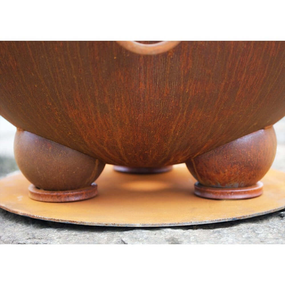 Fire Pit Art Nepal 41-Inch Handcrafted Carbon Steel Gas Fire Pit - Wooden bowl with a textured surface on a stone surface