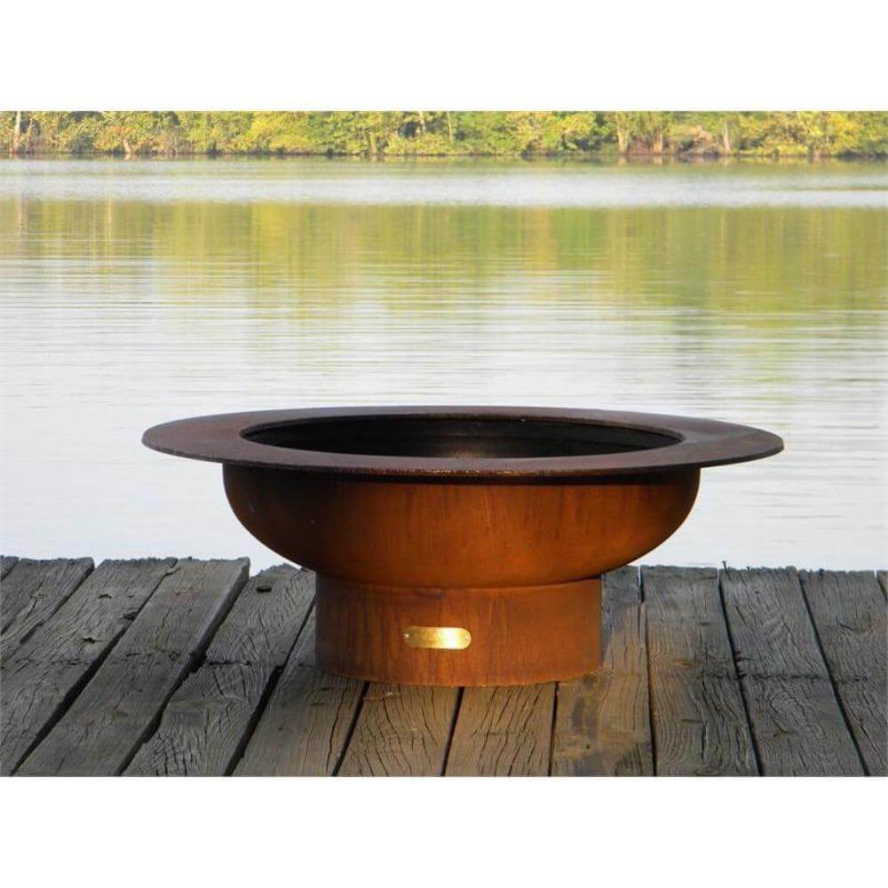 Fire Pit Art Saturn 40-Inch Handcrafted Carbon Steel Fire Pit (SAT) - Rust-colored fire pit on a wooden deck by a lake