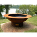 Fire Pit Art Saturn 40-Inch Handcrafted Carbon Steel Gas Fire Pit - Rust-colored fire pit on a stone platform with a lake and trees in the background