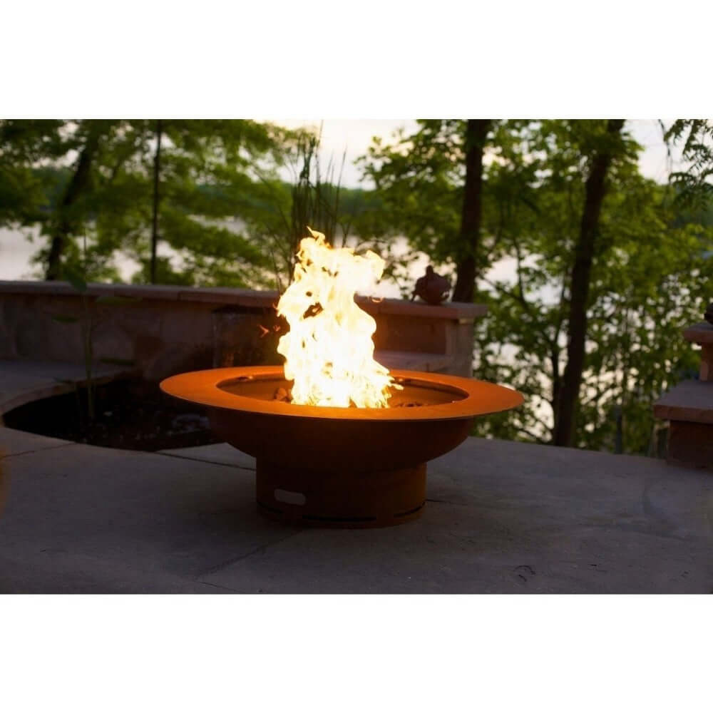 Fire Pit Art Saturn 40-Inch Handcrafted Carbon Steel Gas Fire Pit - Fire pit with flames burning in an outdoor setting with trees and water in the background