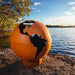 Fire Pit Art Third Rock Globe Shaped 36-Inch Carbon Steel Fire Pit (TR) - Orange globe with world map design on a rock by a lake