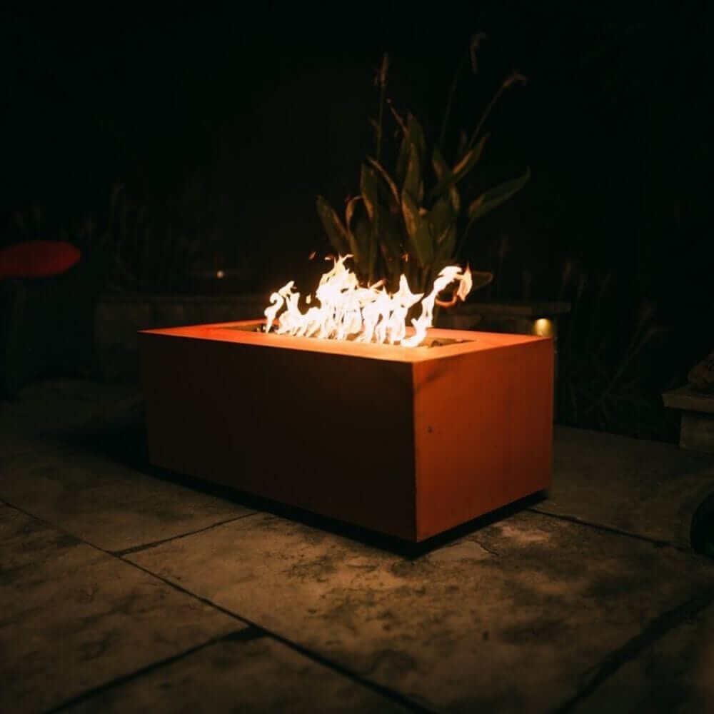 Fire Pit Art Linear 48-Inch Handcrafted Carbon Steel Gas Fire Pit - Fire pit with flames burning on a stone patio at night