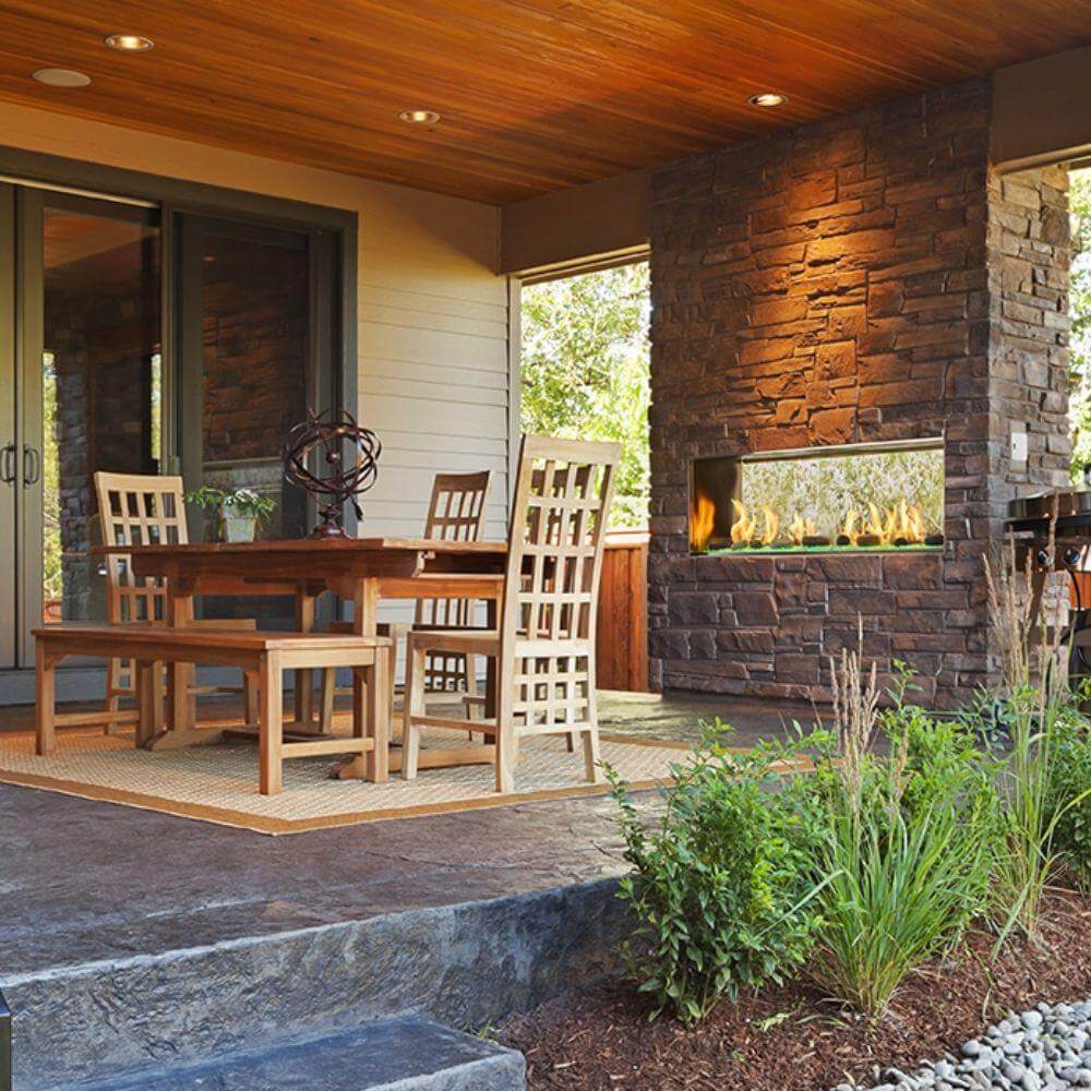 Modern outdoor patio with a wooden dining set and a stylish two-sided gas fireplace for a cozy ambiance.