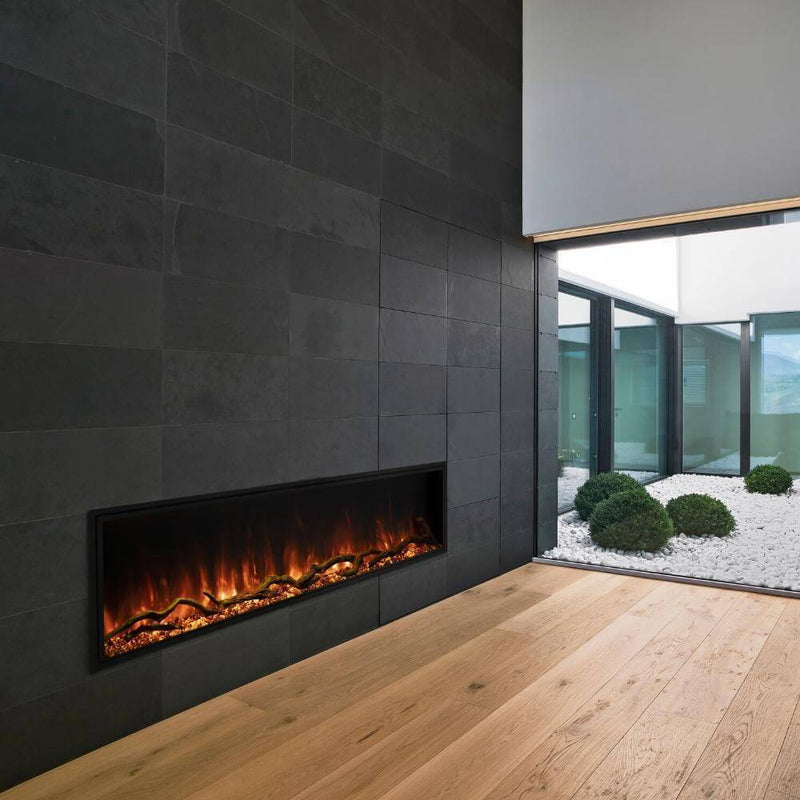 "Landscape Pro Slim" Smart Electric Fireplace - Modern living space featuring a sleek electric fireplace set into a dark stone wall, with a minimalist outdoor garden visible through glass.
