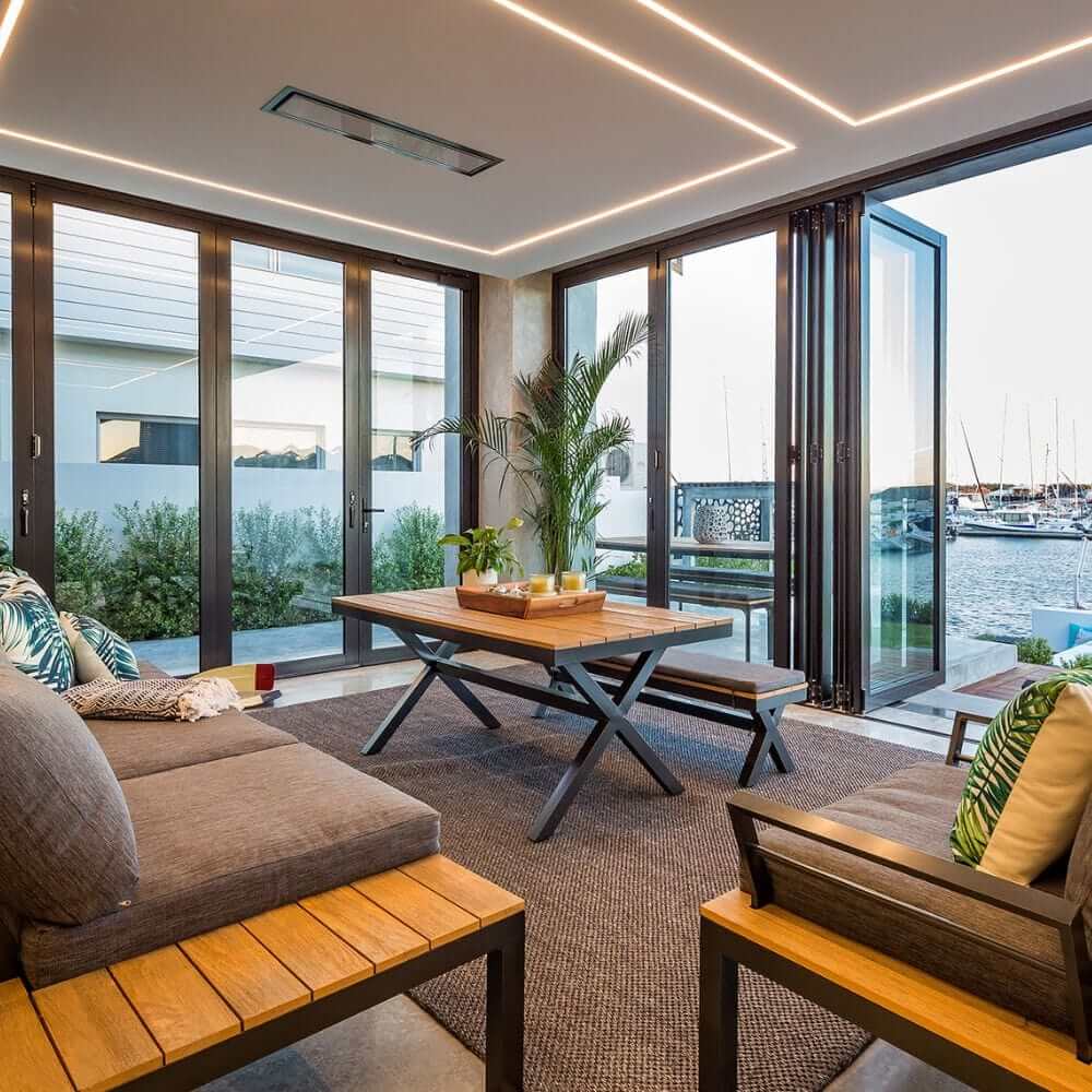 Modern indoor living space with sleek furniture, large windows, and views of a marina.