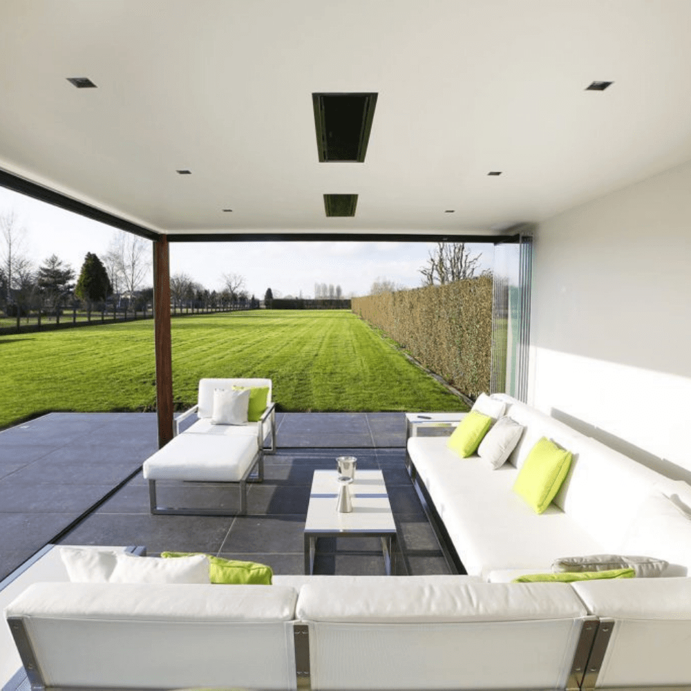 Modern outdoor living space featuring a sleek white sofa set with green cushions and a scenic garden view.