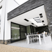 Modern outdoor patio with minimalist design and sleek dining area featuring a Bromic heater for warmth.