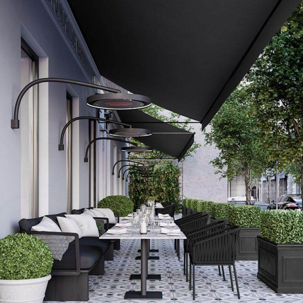 Stylish outdoor dining area featuring Bromic Eclipse electric heaters and elegant furnishings.