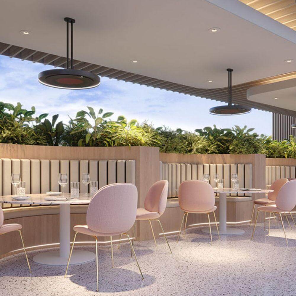 Stylish restaurant interior featuring pink chairs, elegant tables, and Bromic Eclipse heaters for warmth.