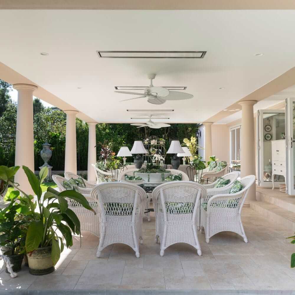 Stylish patio area with wicker furniture, ceiling fan, and elegant decor, perfect for outdoor relaxation.