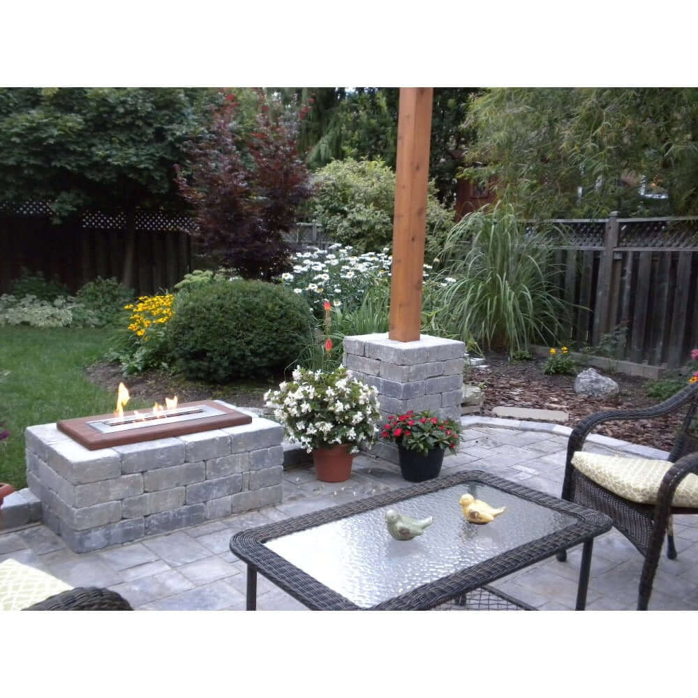 The Bio Flame 24-Inch Indoor/Outdoor Ethanol Fireplace Burner - Cozy patio featuring a warm fire pit surrounded by inviting wicker furniture