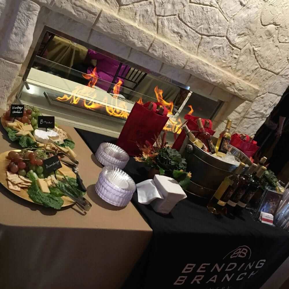 The Bio Flame 72-Inch Firebox DS - Built-in See-Through Ethanol Fireplace - A colorful spread of delectable dishes and drinks on a buffet table featuring a see-through fireplace