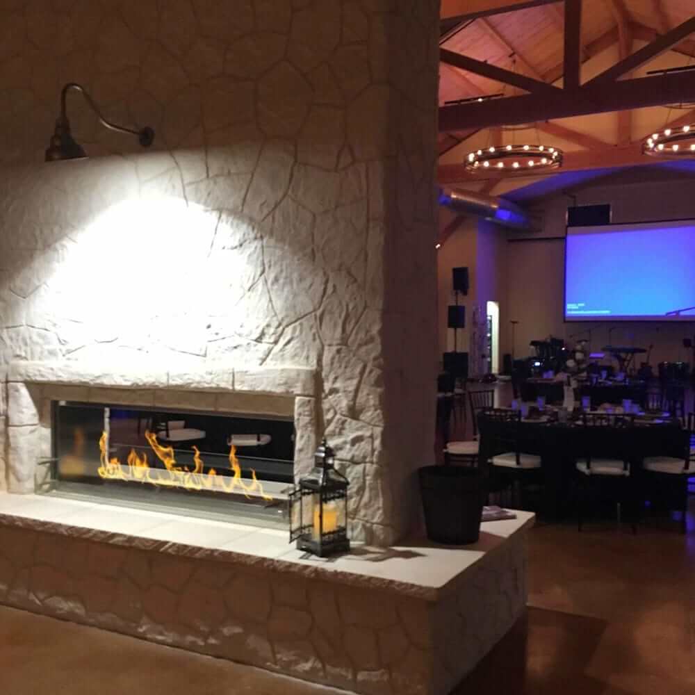 The Bio Flame 72-Inch Firebox DS - Built-in See-Through Ethanol Fireplace - A cozy room featuring a large fireplace beside a projector screen