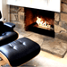 The Bio Flame Fireplace Insert Kit 38-Inch Ethanol Burner with Grate - A contemporary black leather chair and ottoman set against a flickering fireplace